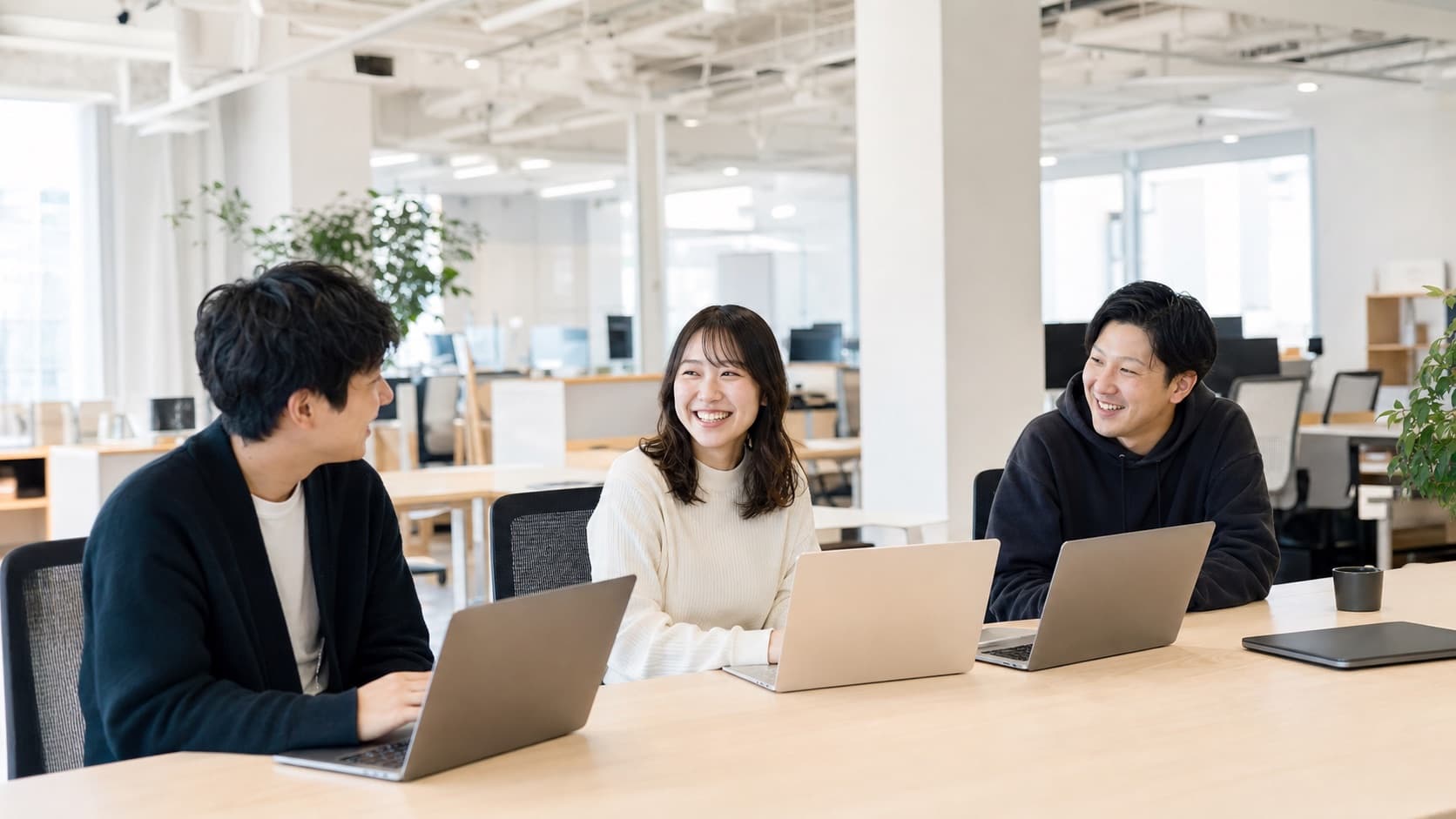 明るいオフィスでチームが談笑しながら働く様子
